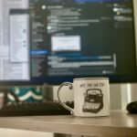 white and black ceramic mug beside black computer mouse